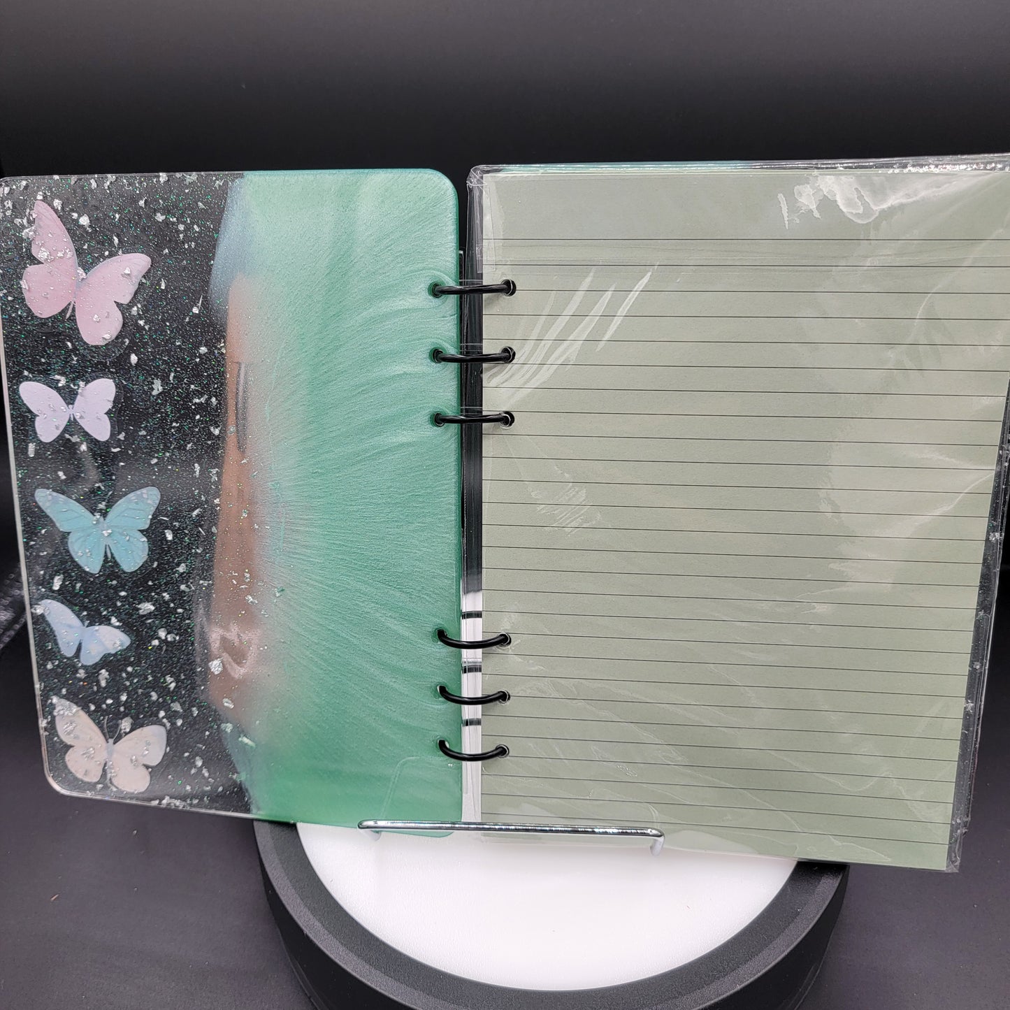 Notebook with a clear plastic cover displaying butterfly designs on a dark background.