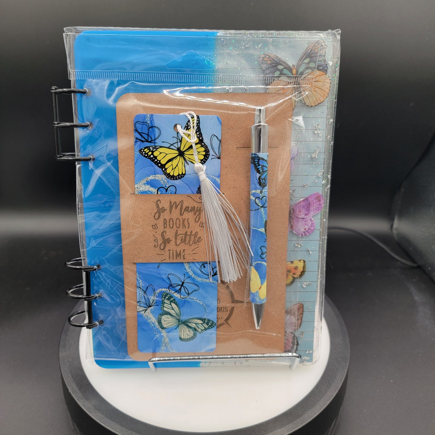 Notebook with butterfly design on cover, pen, and ruler inside a clear plastic sleeve.
