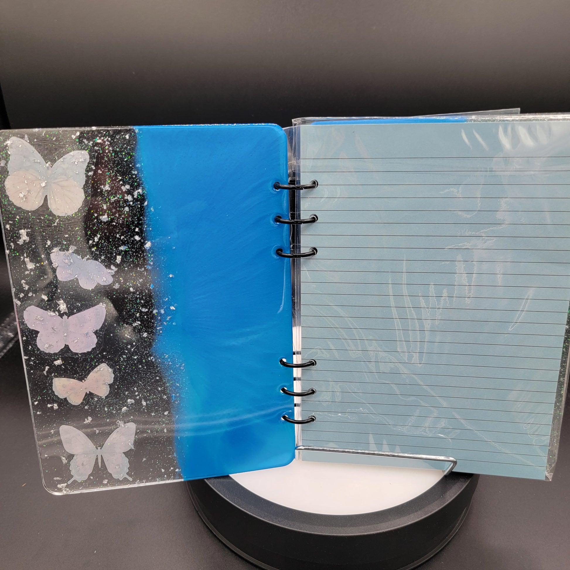 Notebook with blue cover featuring butterfly designs on a dark surface