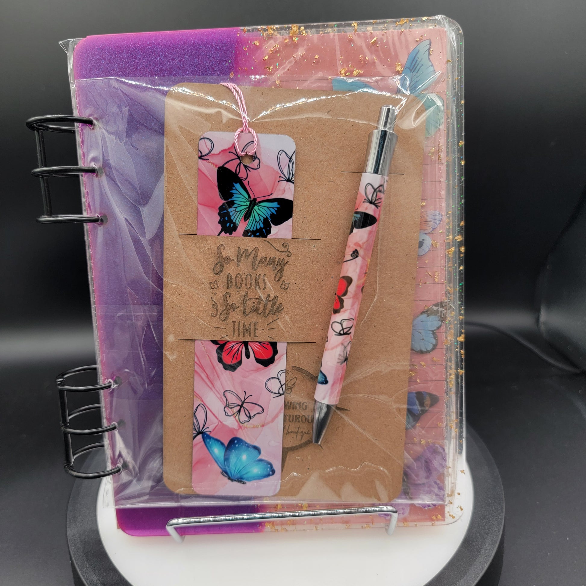 Notebook with pen and decorative elements in a clear plastic sleeve on a dark background