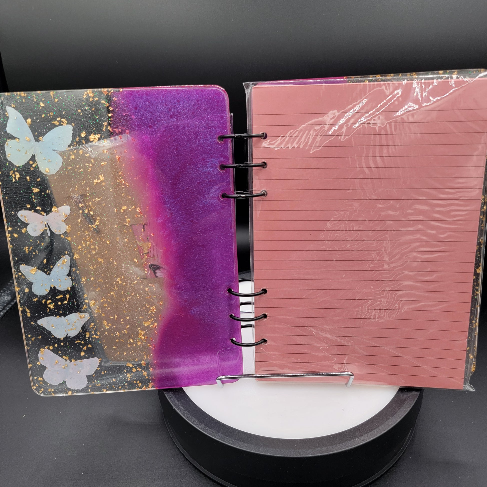 Notebook with pink cover and butterfly design on a dark background