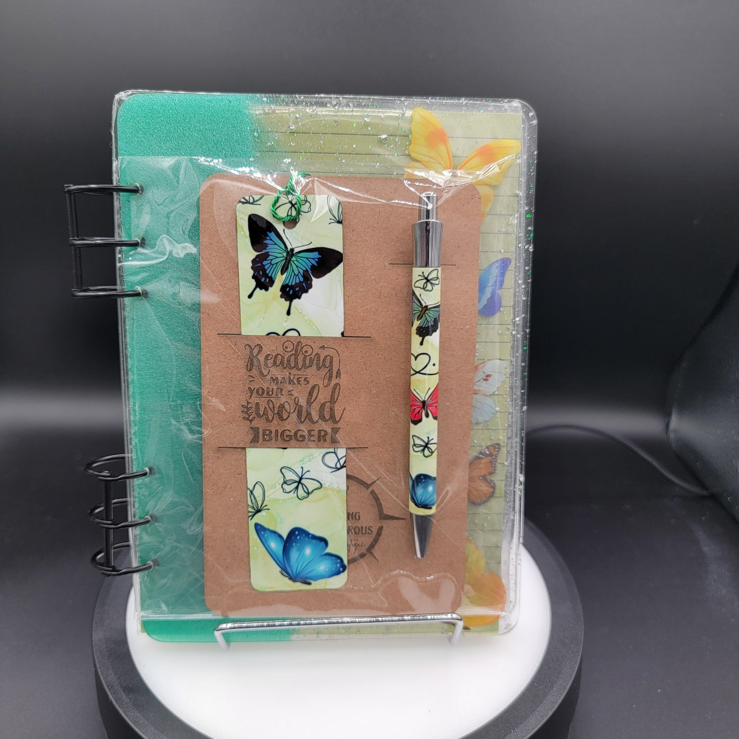 Notebook with butterfly designs and a pen on a dark background