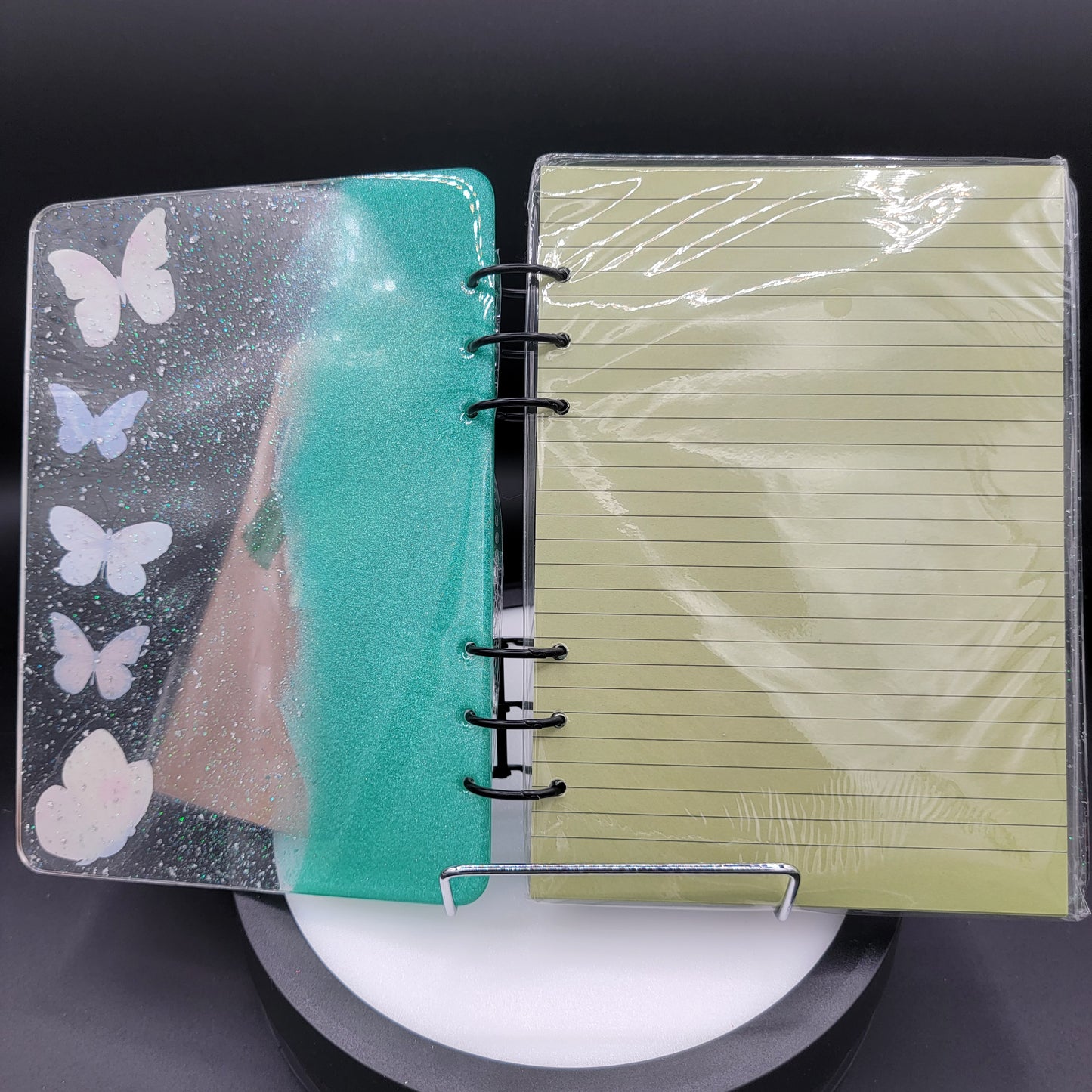 Notebook with a green cover featuring butterfly designs on a dark background