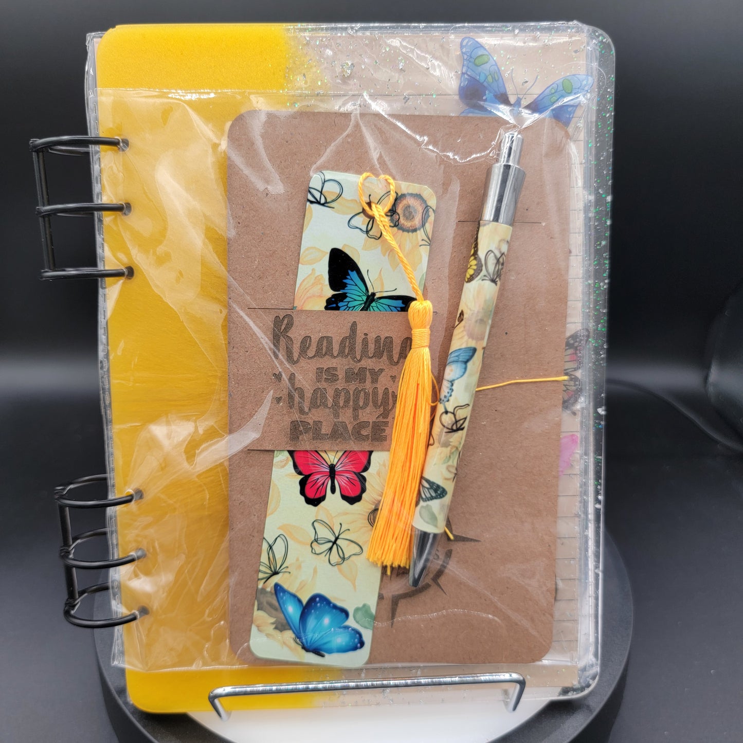 Notebook with butterfly-themed bookmarks and a pen on a dark surface