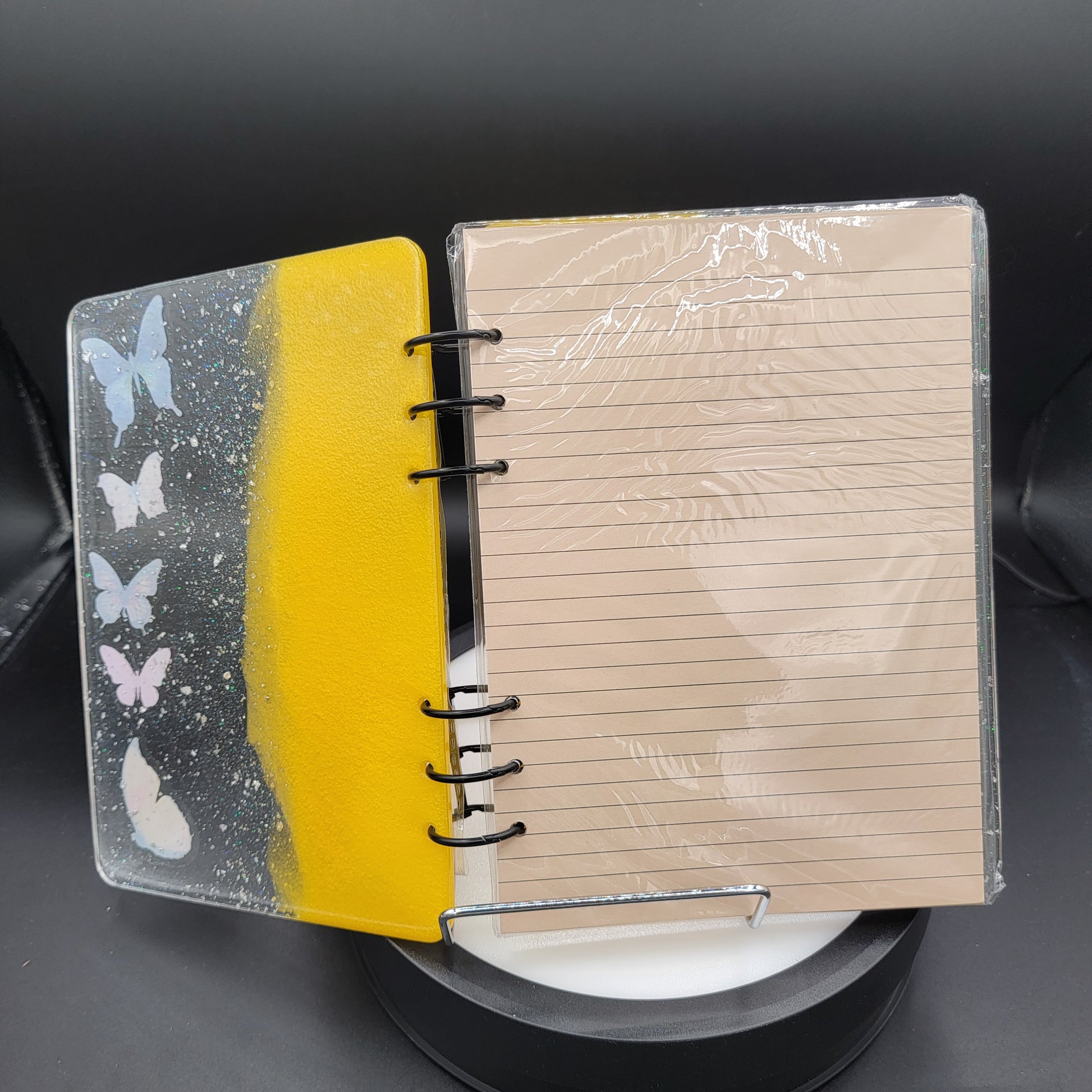 Notebook with a yellow cover featuring butterfly designs on a dark background