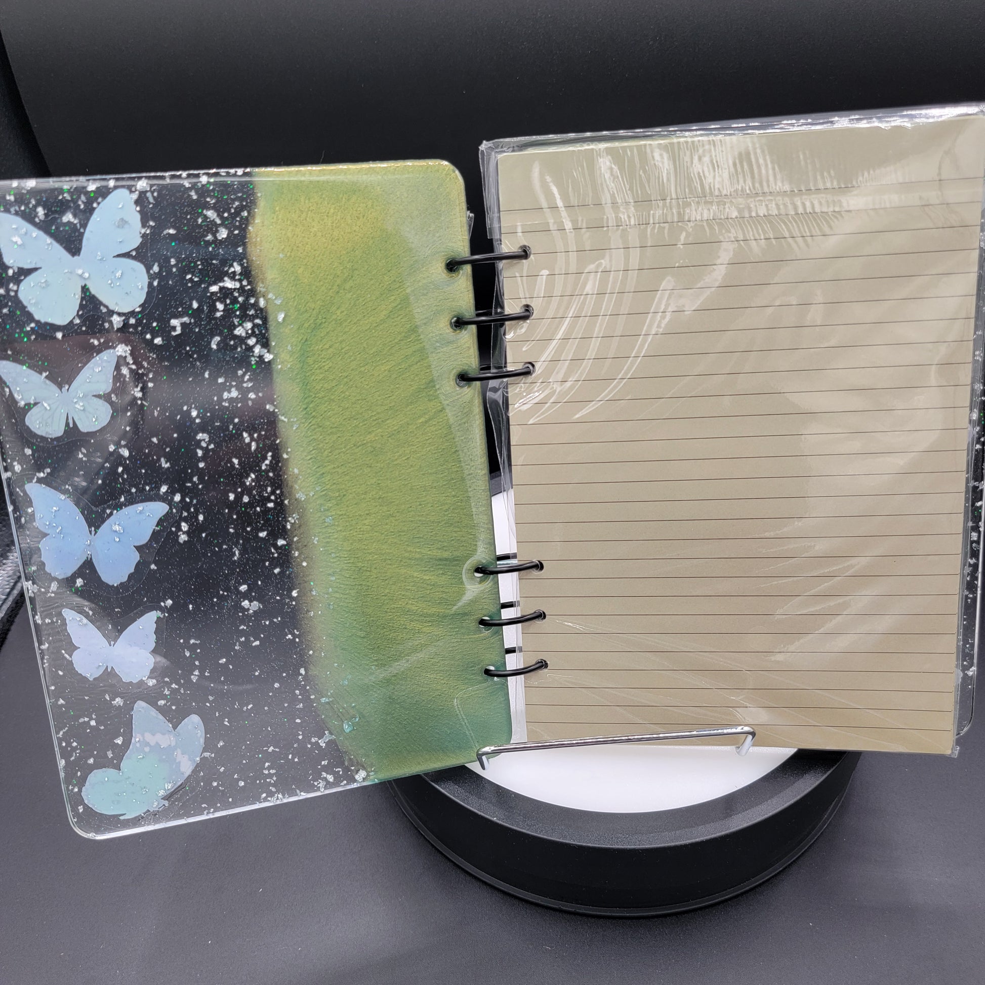 Notebook with a clear cover featuring butterfly designs on a dark surface