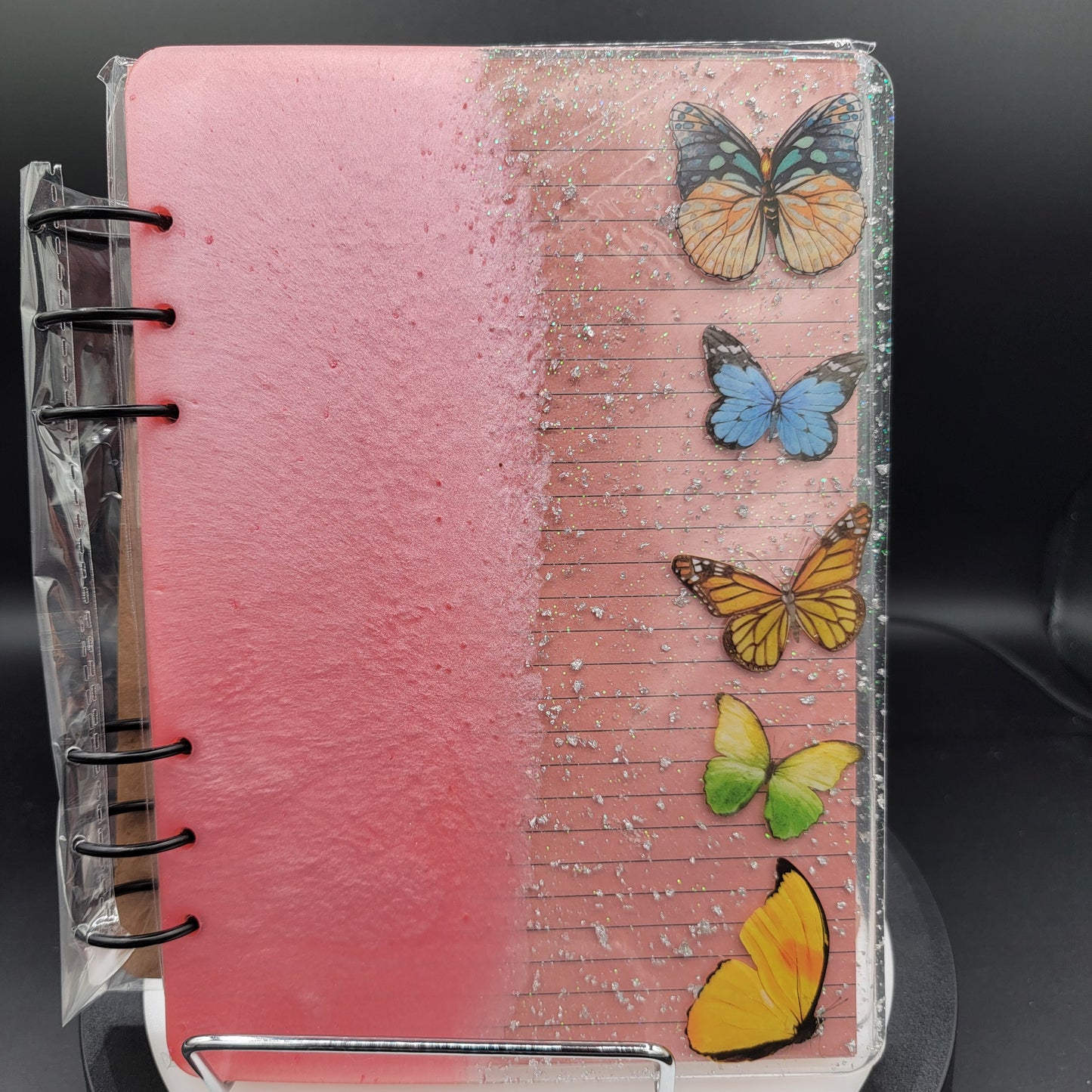 Notebook with pink cover and colorful butterflies on a black background