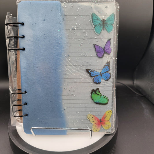 Small notebook with colorful butterfly stickers on a black background