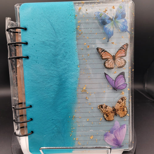 Notebook with butterfly designs on a clear cover against a dark background