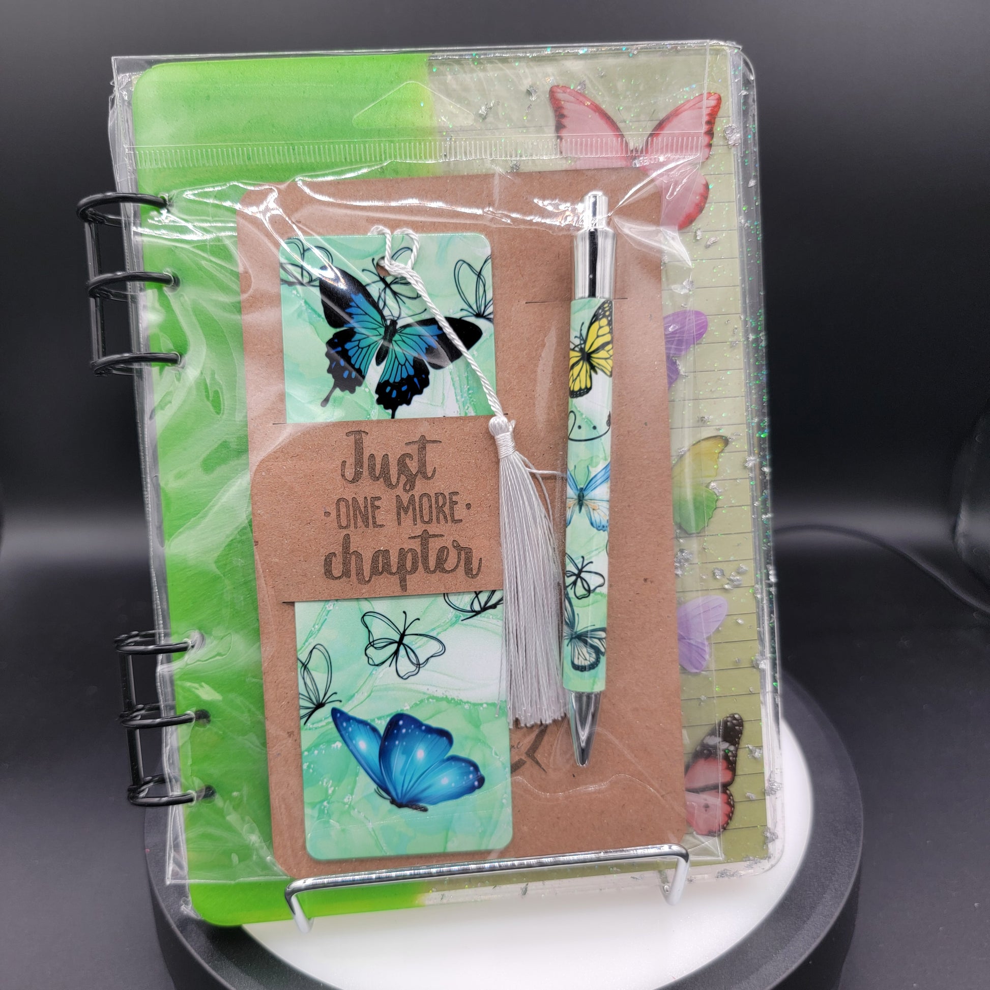 Notebook with butterfly designs and a pen on a dark surface