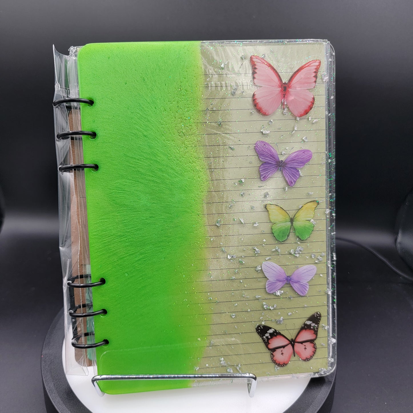 Notebook with colorful butterfly designs on a clear stand against a dark background