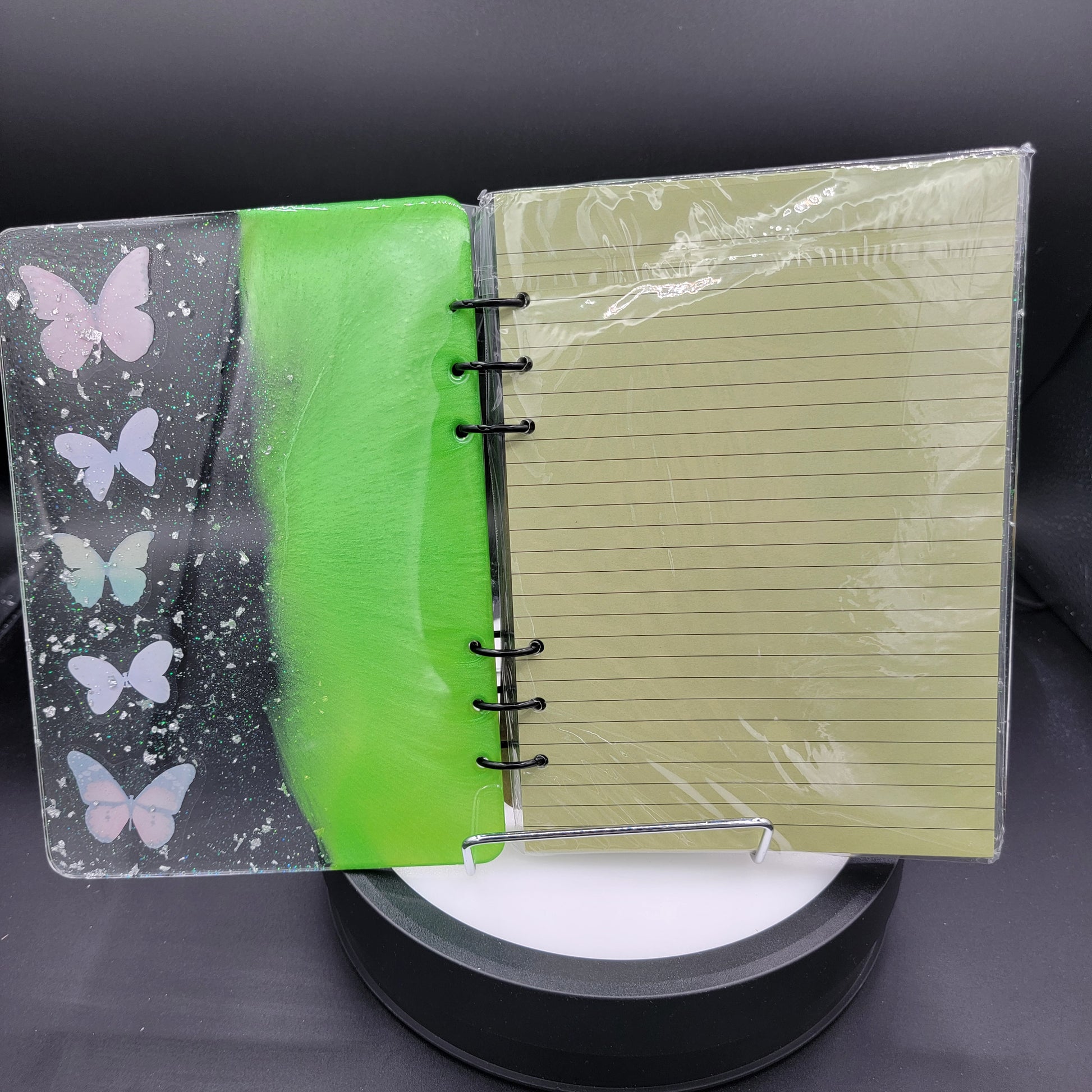 Notebook with green cover featuring butterfly designs on a dark background