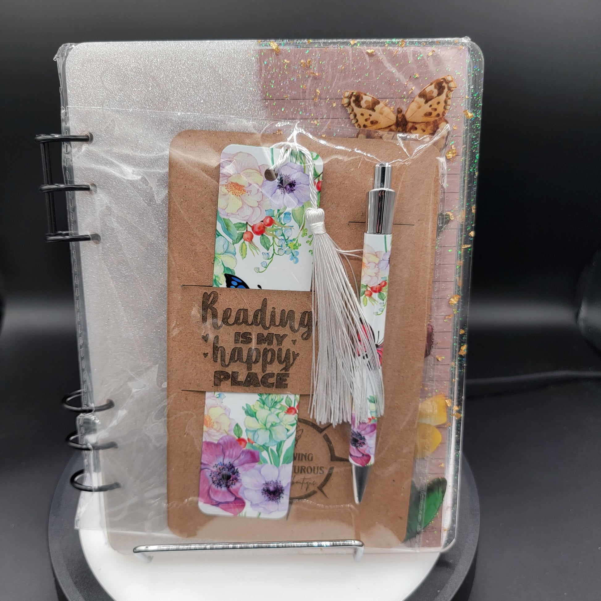 Notebook with floral bookmarks and a pen on a white surface